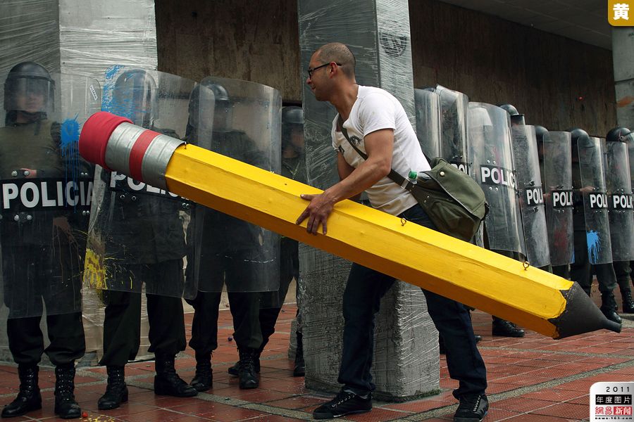 2011年11月10日，哥伦比亚首都波哥大，一名抗议学生用巨大的铅笔模型挑衅防暴警察。哥.jpg